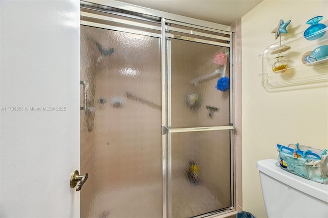 bathroom with a shower with shower door and toilet