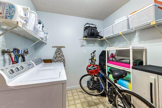 laundry area with laundry area, baseboards, a textured ceiling, and washing machine and clothes dryer