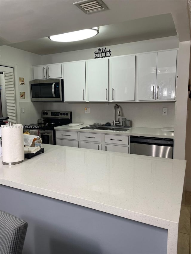 kitchen featuring appliances with stainless steel finishes, sink, and white cabinets