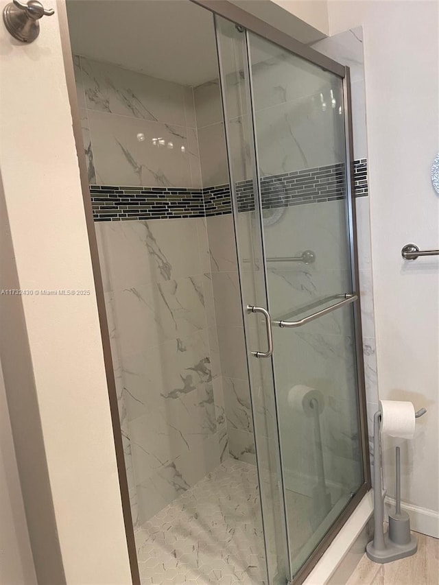 bathroom with hardwood / wood-style flooring and an enclosed shower