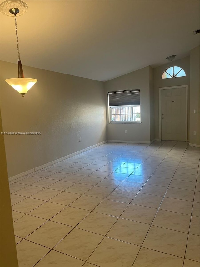 tiled empty room featuring lofted ceiling