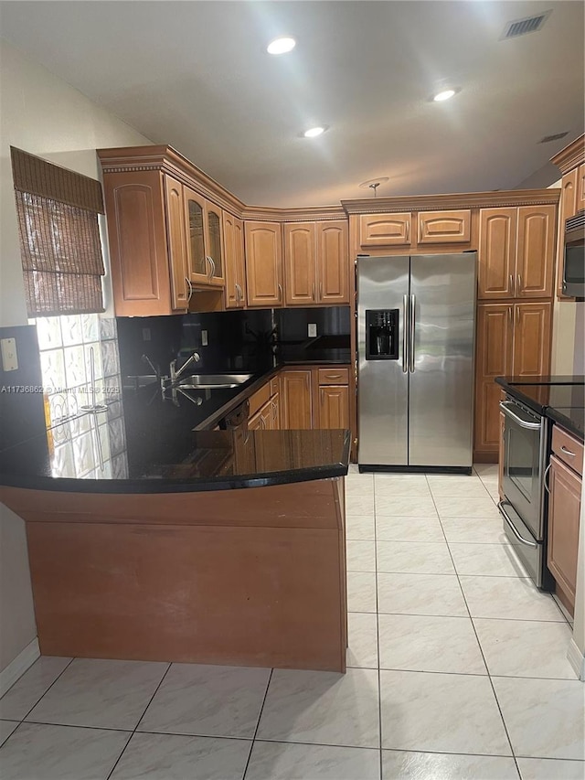 kitchen with sink, dark stone countertops, backsplash, light tile patterned floors, and stainless steel appliances