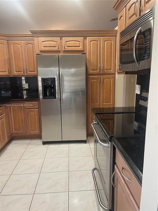 kitchen featuring stainless steel appliances, tasteful backsplash, light tile patterned floors, and dark stone counters