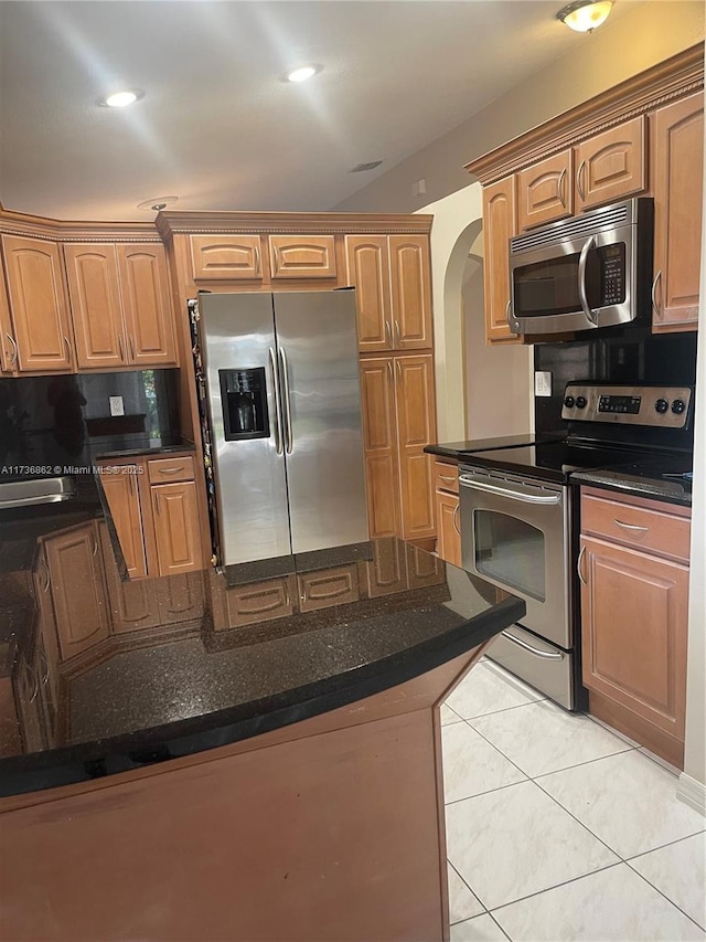 kitchen with light tile patterned floors, sink, dark stone counters, and appliances with stainless steel finishes