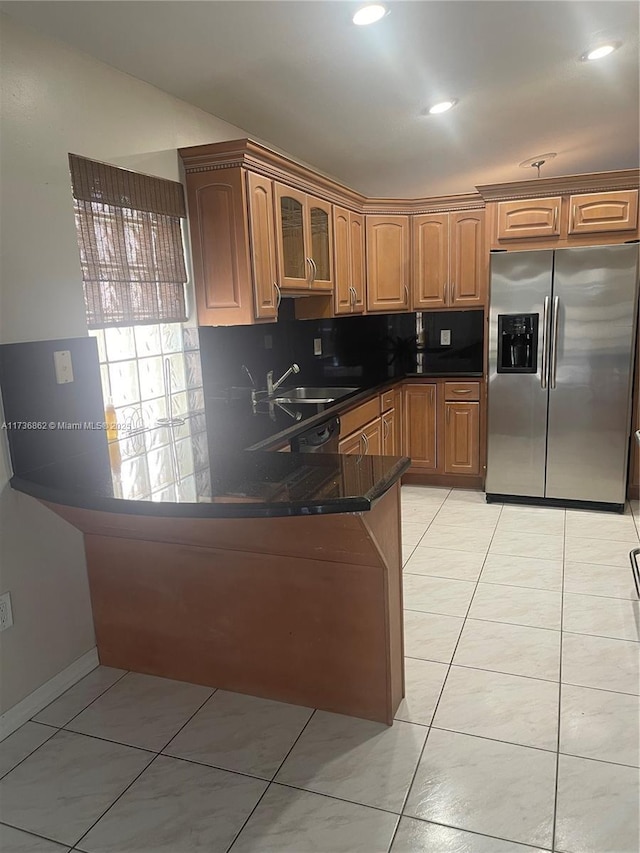 kitchen with light tile patterned floors, glass insert cabinets, a peninsula, stainless steel refrigerator with ice dispenser, and backsplash