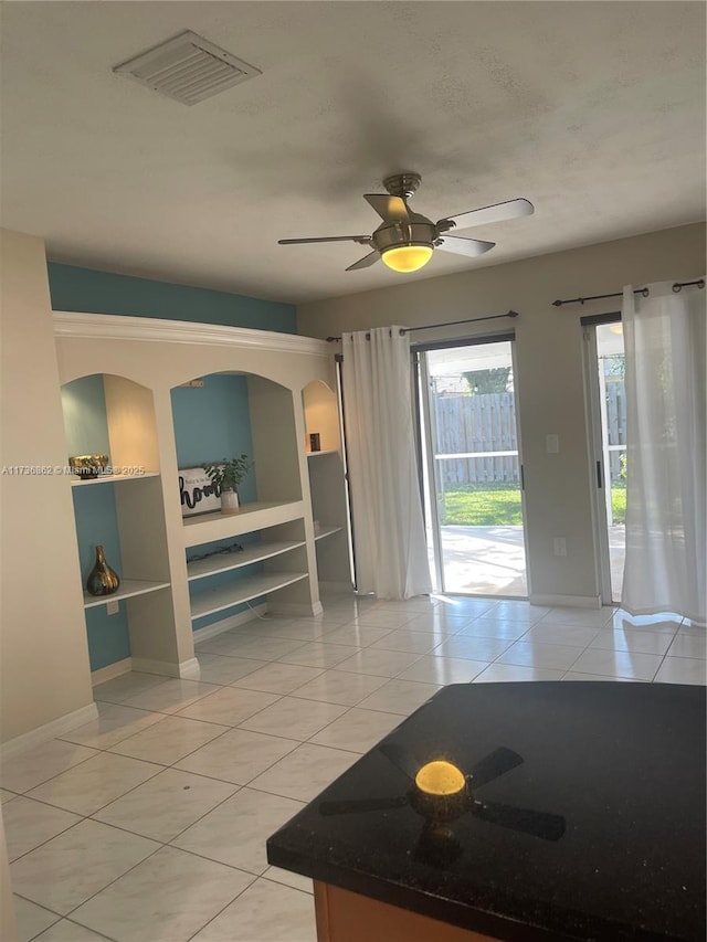 interior space with light tile patterned floors, baseboards, visible vents, and a ceiling fan