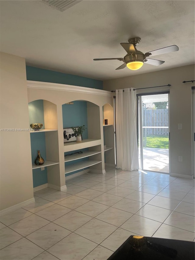 unfurnished room featuring ceiling fan, built in features, baseboards, and light tile patterned flooring