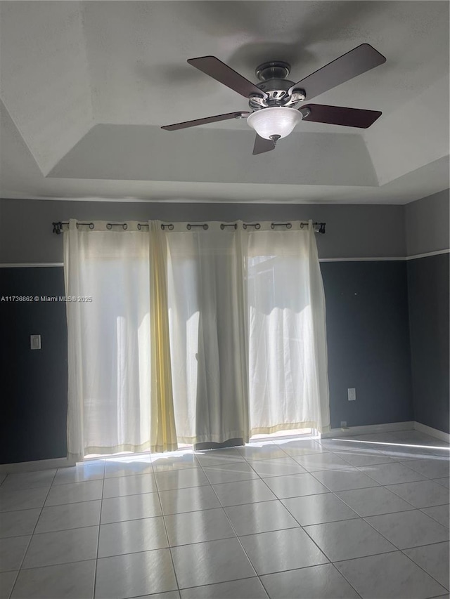 tiled spare room with a raised ceiling and a healthy amount of sunlight