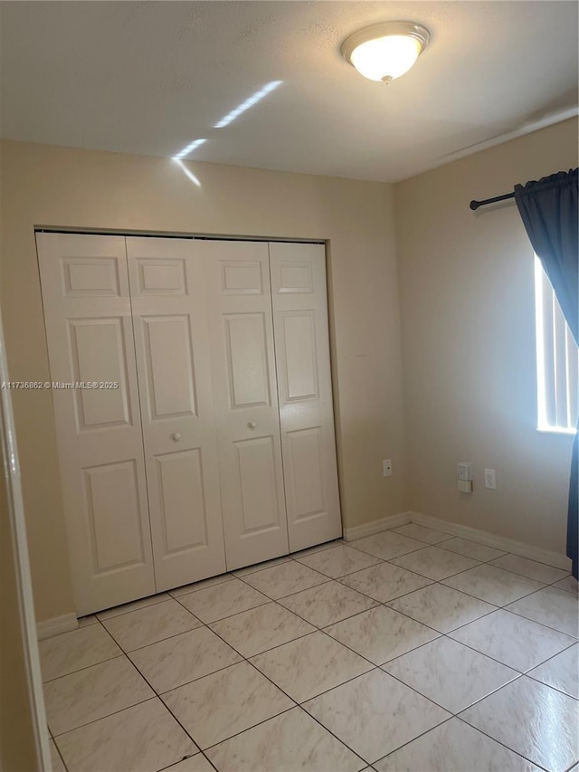 unfurnished bedroom with light tile patterned floors and a closet