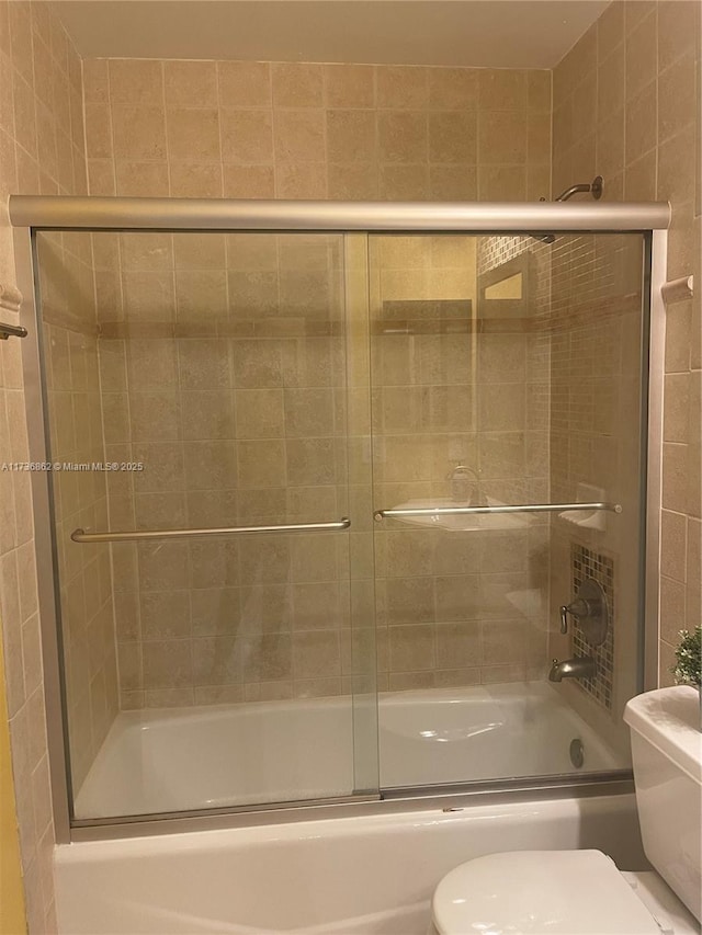 bathroom with bath / shower combo with glass door and toilet