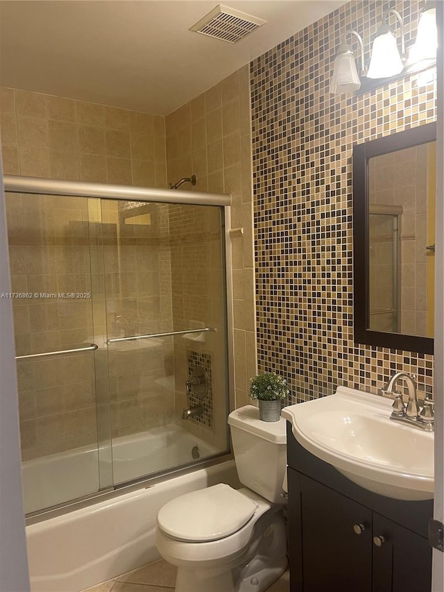 full bathroom with shower / bath combination with glass door, tile walls, visible vents, vanity, and tile patterned flooring