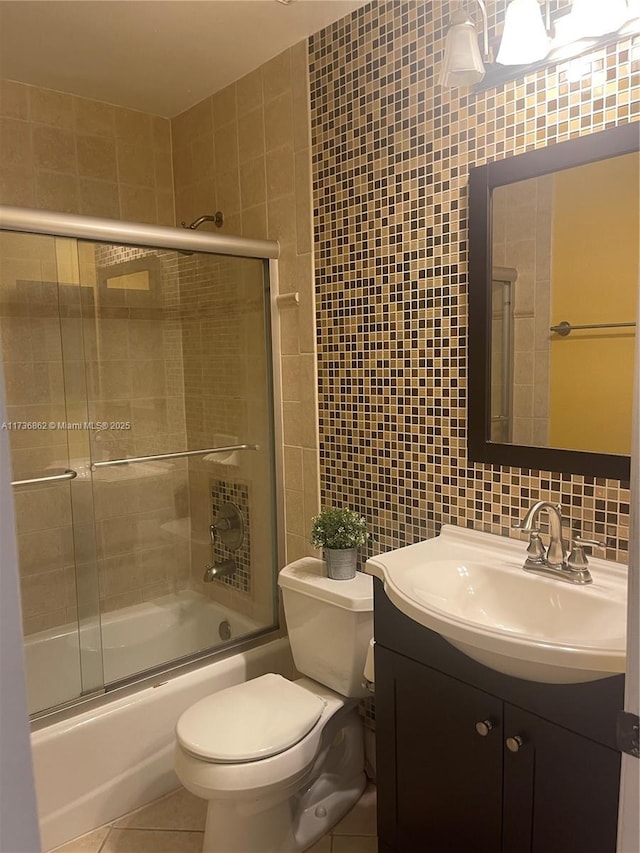 bathroom with vanity, combined bath / shower with glass door, tile patterned flooring, and tile walls