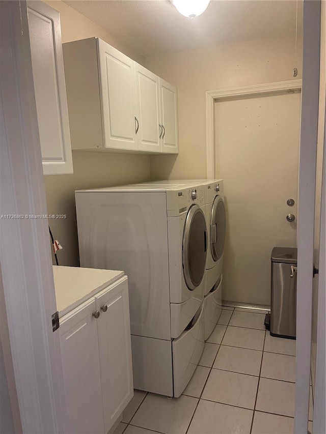 laundry area with cabinets, light tile patterned flooring, and washer and clothes dryer