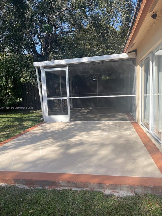 view of patio with fence and a sunroom