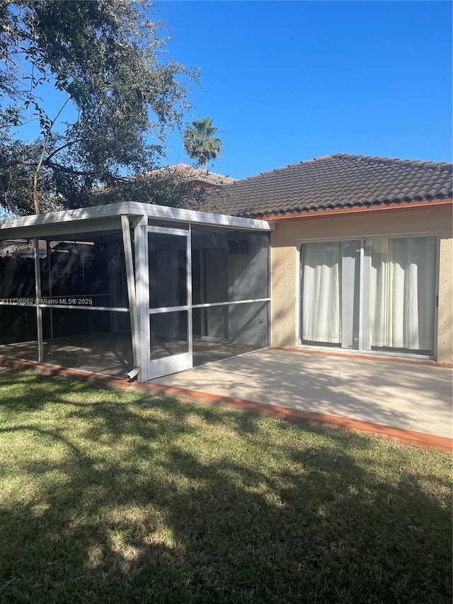 rear view of property featuring a patio, a sunroom, and a yard