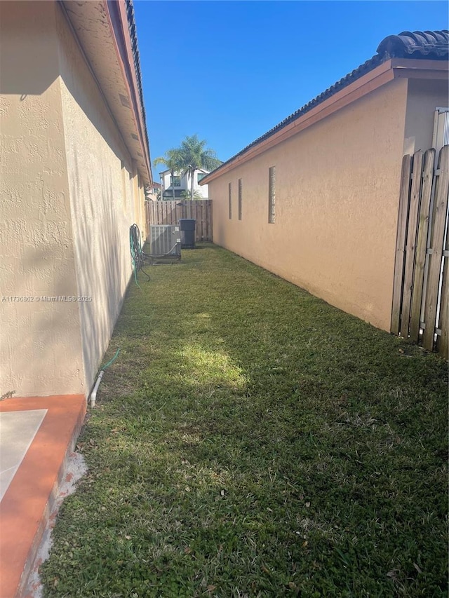 view of yard with central AC unit and fence