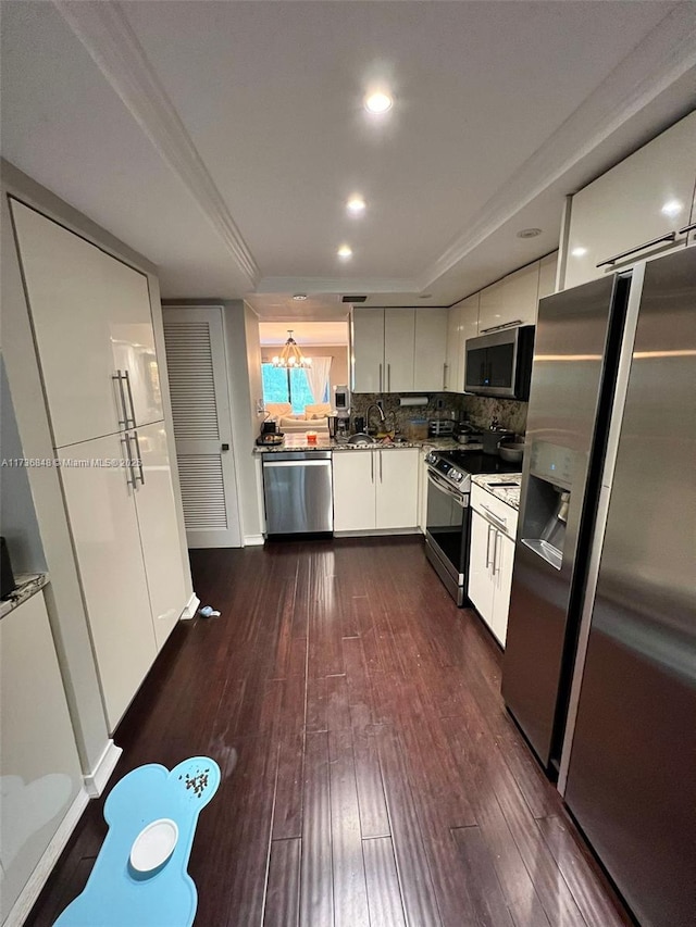 kitchen with sink, stainless steel appliances, white cabinets, dark hardwood / wood-style flooring, and decorative backsplash