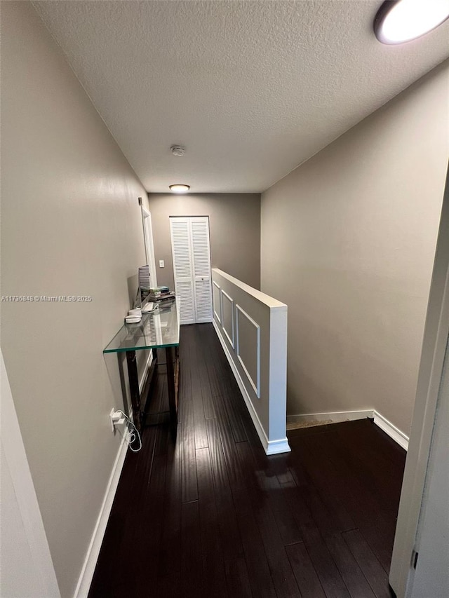 corridor featuring dark wood-type flooring and a textured ceiling