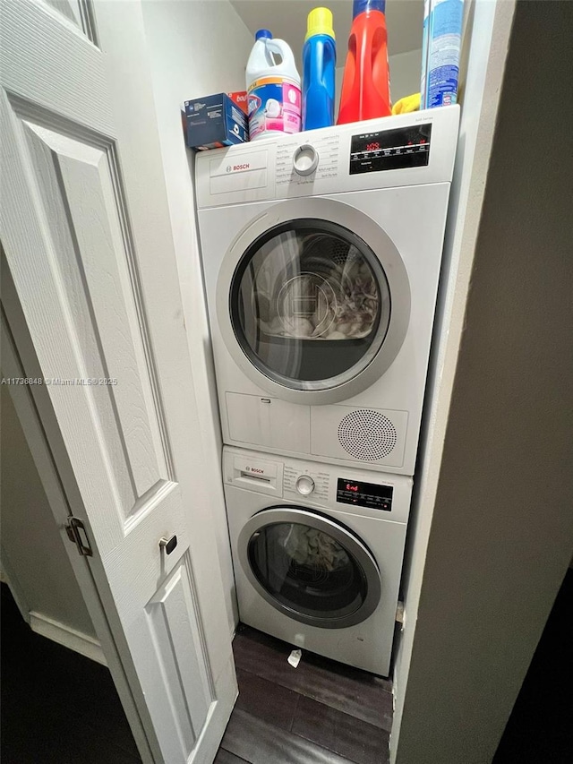 laundry room featuring dark hardwood / wood-style flooring and stacked washer / drying machine