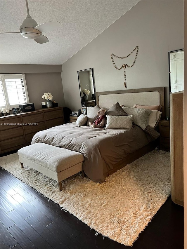 bedroom featuring ceiling fan, lofted ceiling, dark wood-type flooring, and a textured ceiling