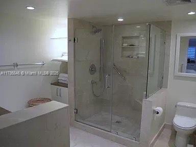 bathroom featuring toilet and a shower with shower door