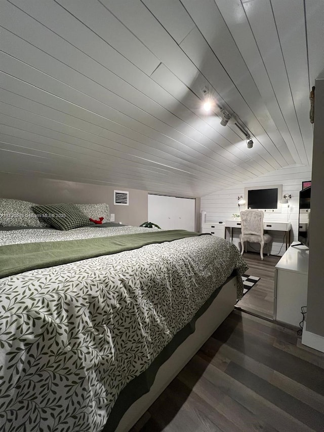 bedroom featuring wood-type flooring, rail lighting, and vaulted ceiling