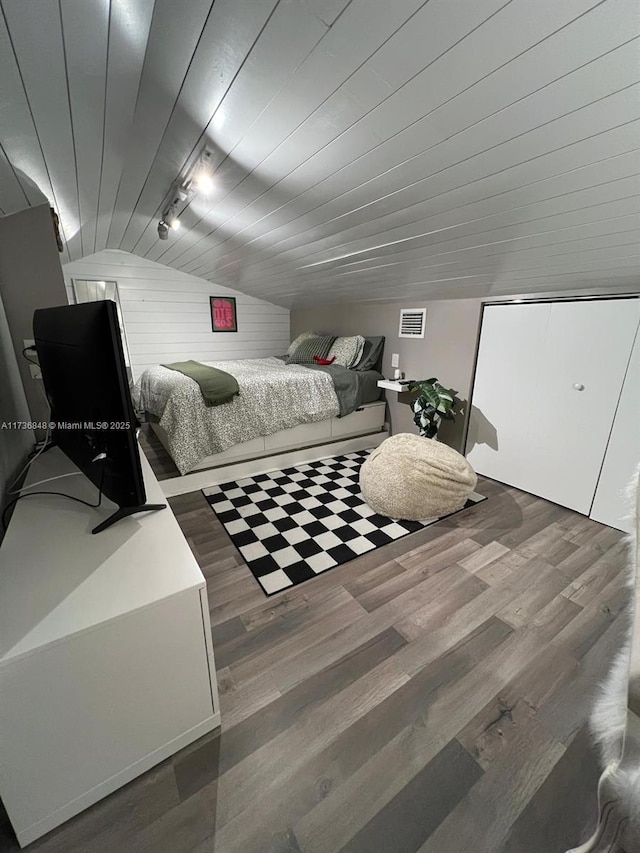 bedroom with vaulted ceiling, rail lighting, dark wood-type flooring, and wood ceiling