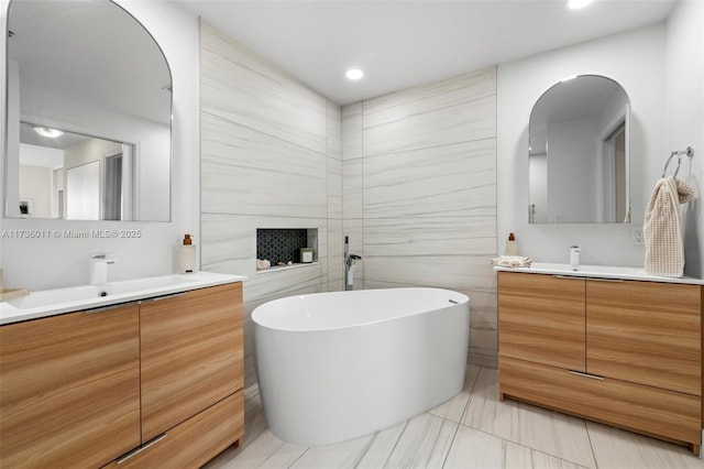 bathroom featuring vanity, tile walls, and a tub to relax in