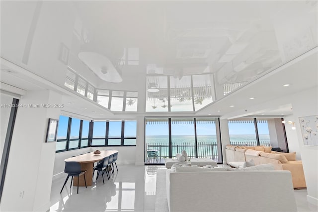 tiled living room with a water view and a high ceiling