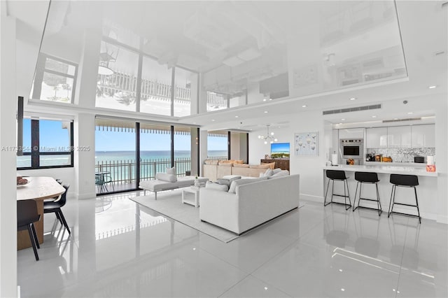 tiled living room featuring a high ceiling and a water view