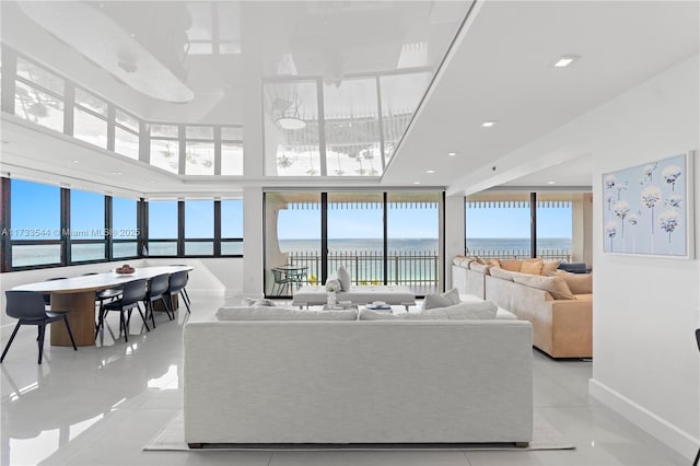 living room featuring a water view, a high ceiling, and light tile patterned floors