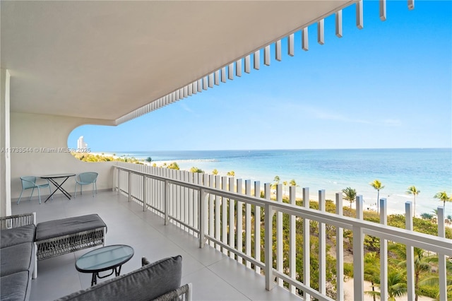 balcony with a water view and a view of the beach