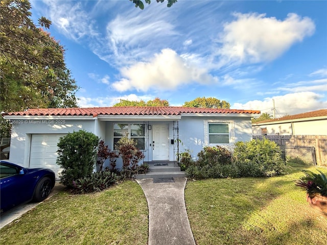 view of front of house featuring stucco siding, a tile roof, an attached garage, fence, and a front yard