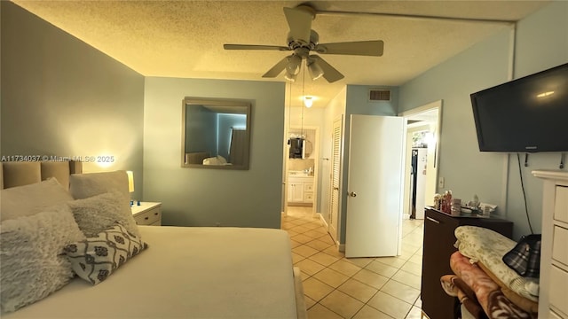 bedroom featuring light tile patterned flooring, ensuite bath, sink, ceiling fan, and a textured ceiling