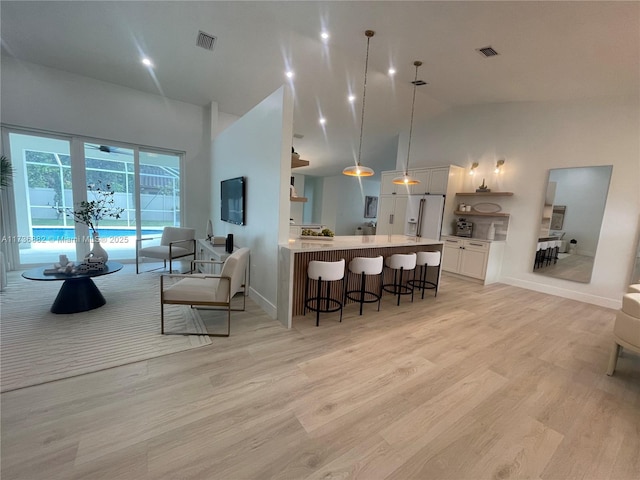 kitchen featuring a peninsula, visible vents, a kitchen breakfast bar, white cabinets, and light countertops