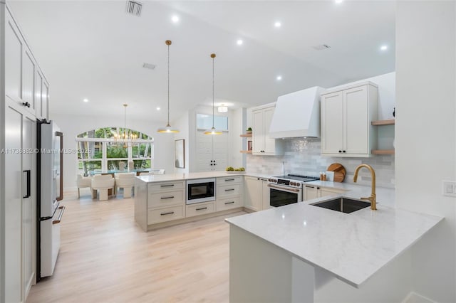 kitchen with a peninsula, built in microwave, premium range hood, open shelves, and a sink