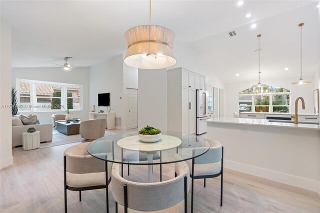 dining space featuring ceiling fan, lofted ceiling, sink, and light wood-type flooring