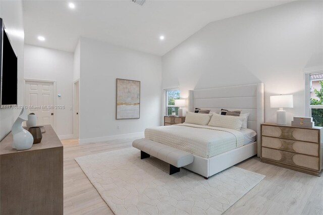 bedroom with high vaulted ceiling and light hardwood / wood-style floors