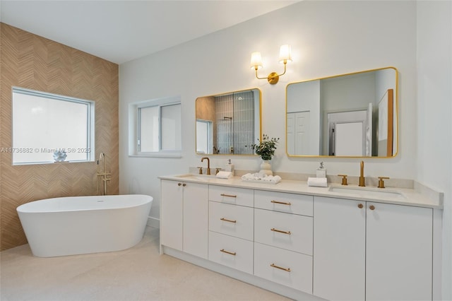 full bath featuring a sink, a freestanding bath, and double vanity