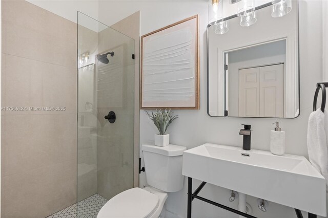 bathroom featuring sink, a tile shower, and toilet