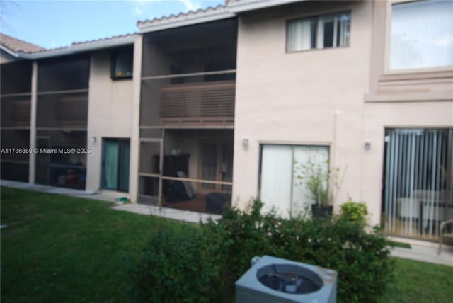 rear view of house with cooling unit and a lawn