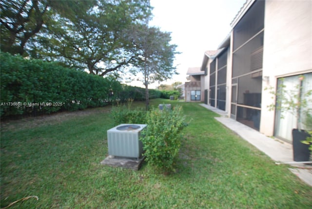 view of yard featuring a sunroom and central AC