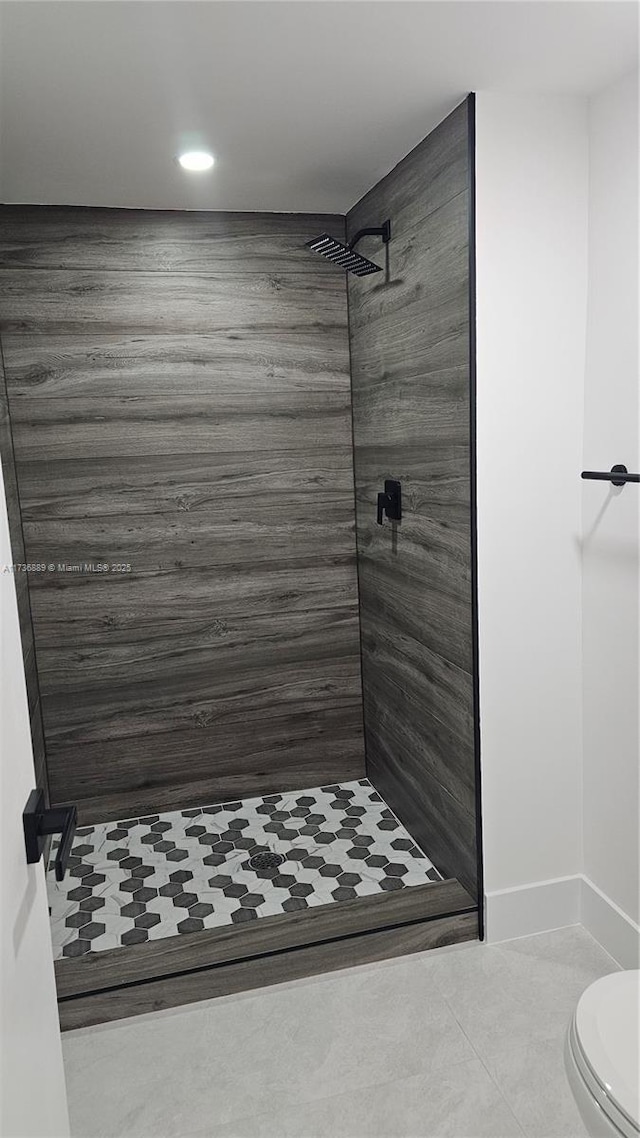 bathroom with tiled shower, tile patterned floors, and toilet