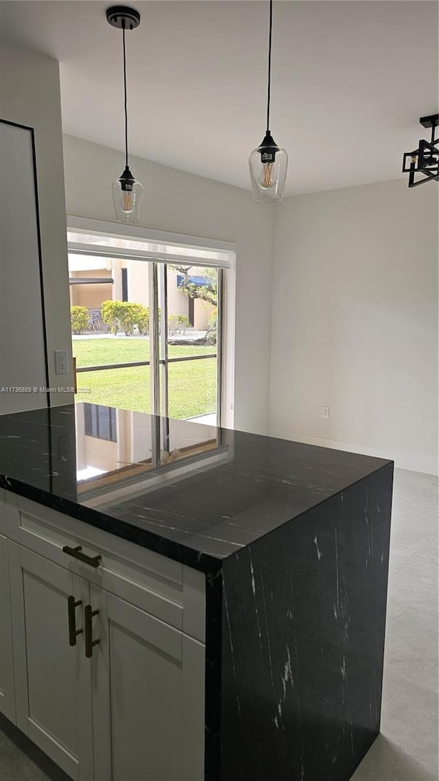 kitchen with dark stone countertops and hanging light fixtures