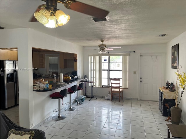 kitchen with ceiling fan, light tile patterned floors, a textured ceiling, and stainless steel fridge with ice dispenser