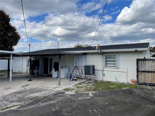 back of house with washing machine and clothes dryer and central air condition unit