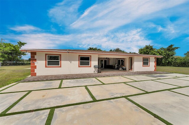 15750 SW 232nd St, Miami, FL 33170 - back of house with stucco siding, a patio area, and a lawn