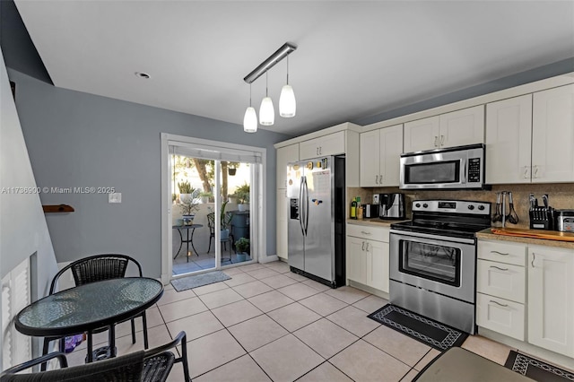 kitchen with decorative backsplash, stainless steel appliances, hanging light fixtures, and white cabinets