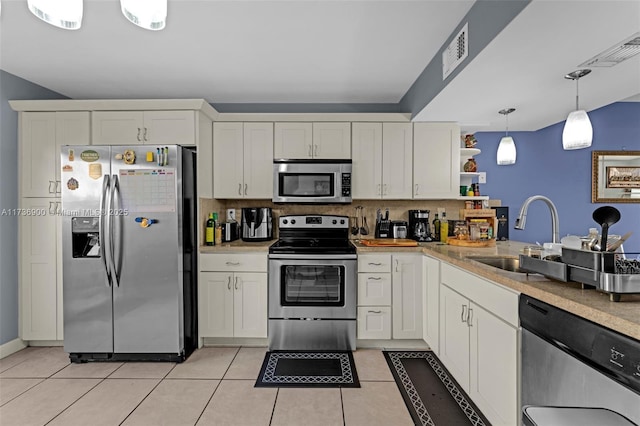 kitchen with sink, tasteful backsplash, light tile patterned floors, appliances with stainless steel finishes, and pendant lighting