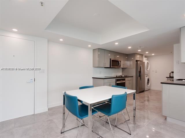 dining space with a tray ceiling and stacked washing maching and dryer